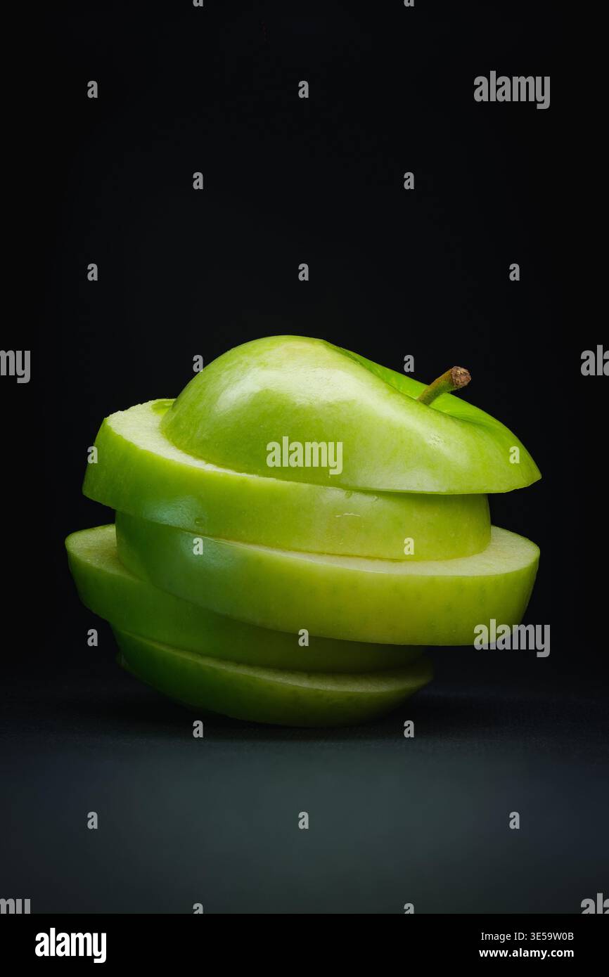 Green apple stacked slices on black background Stock Photo