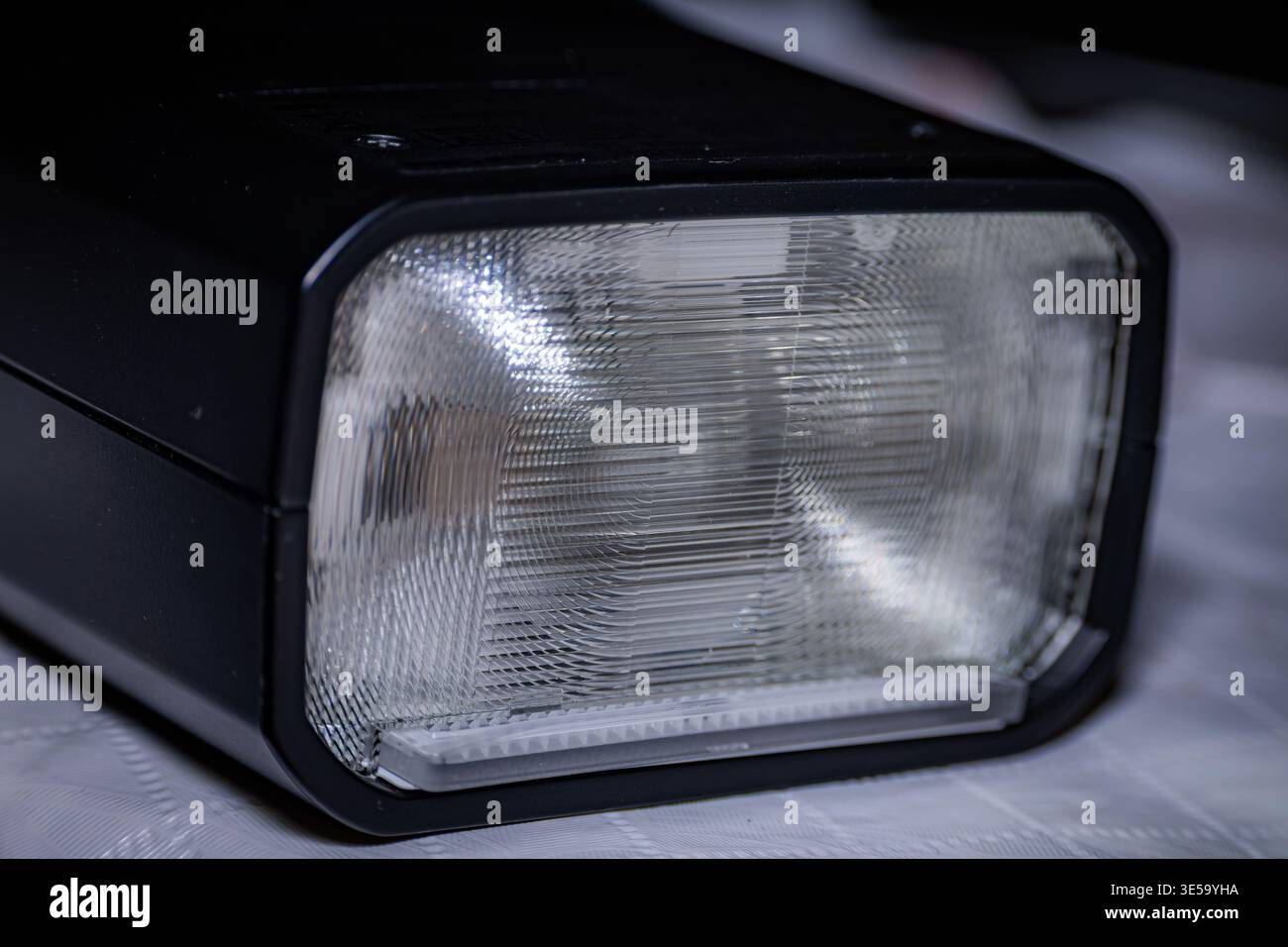 Macro close-up of a photography speedlight flash head showing the textured Fresnel lens and black electronic housing Stock Photo