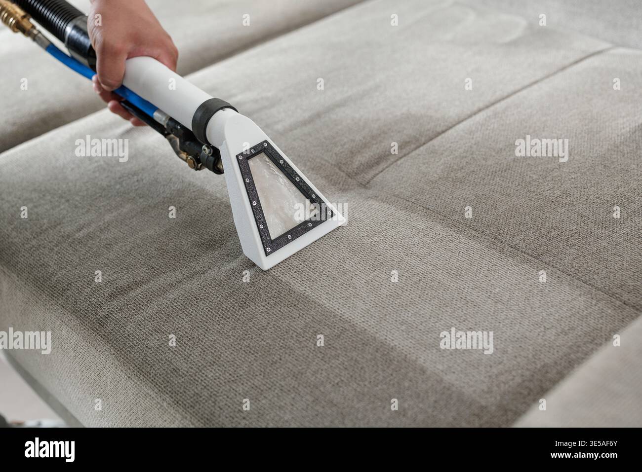 Close-up of professional upholstery extraction cleaning on dirty sofa ...