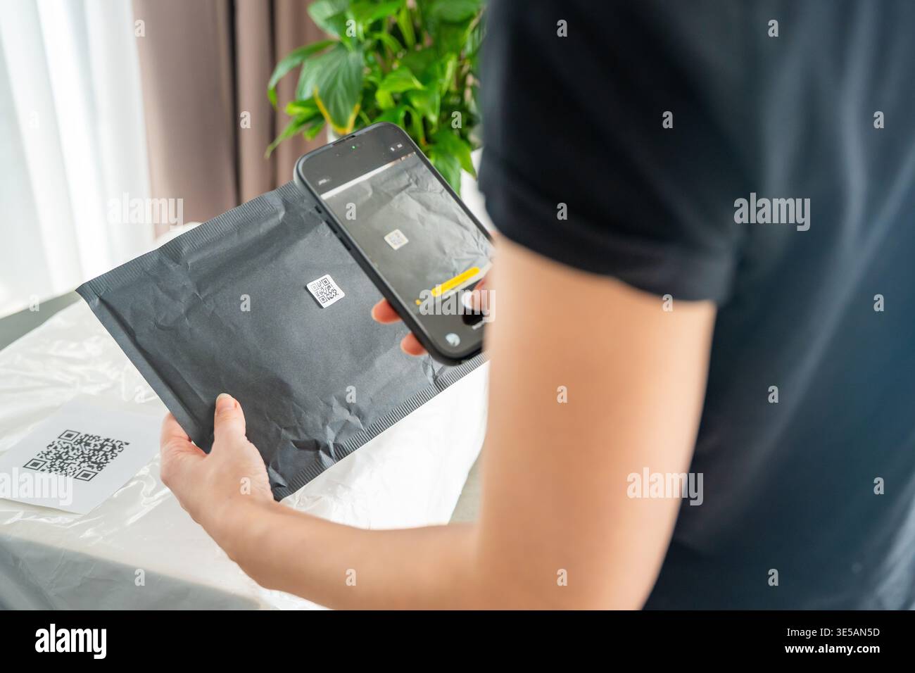 Person scanning QR code on parcel with smartphone camera with focus on mobile device screen. Digital app interface and contactless delivery service Stock Photo