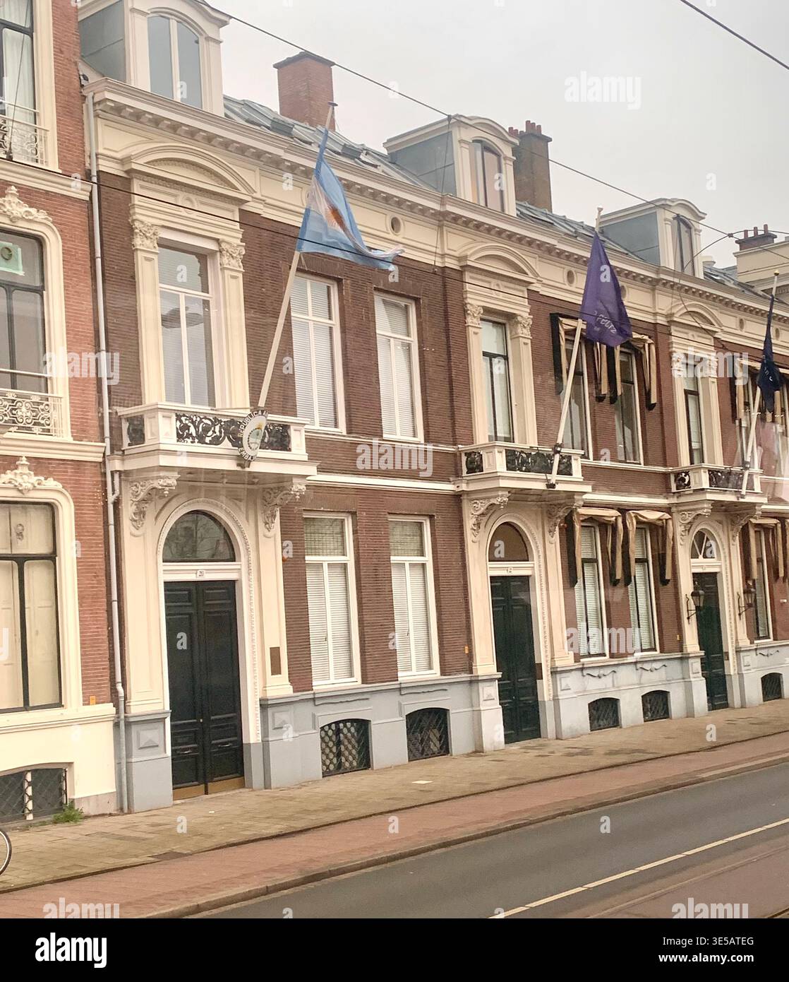Historic European style townhouse with decorative facade and coloured flags displayed on the upper floors overlooking a tram lined street in Hague - Smartphone Captured Stock Image