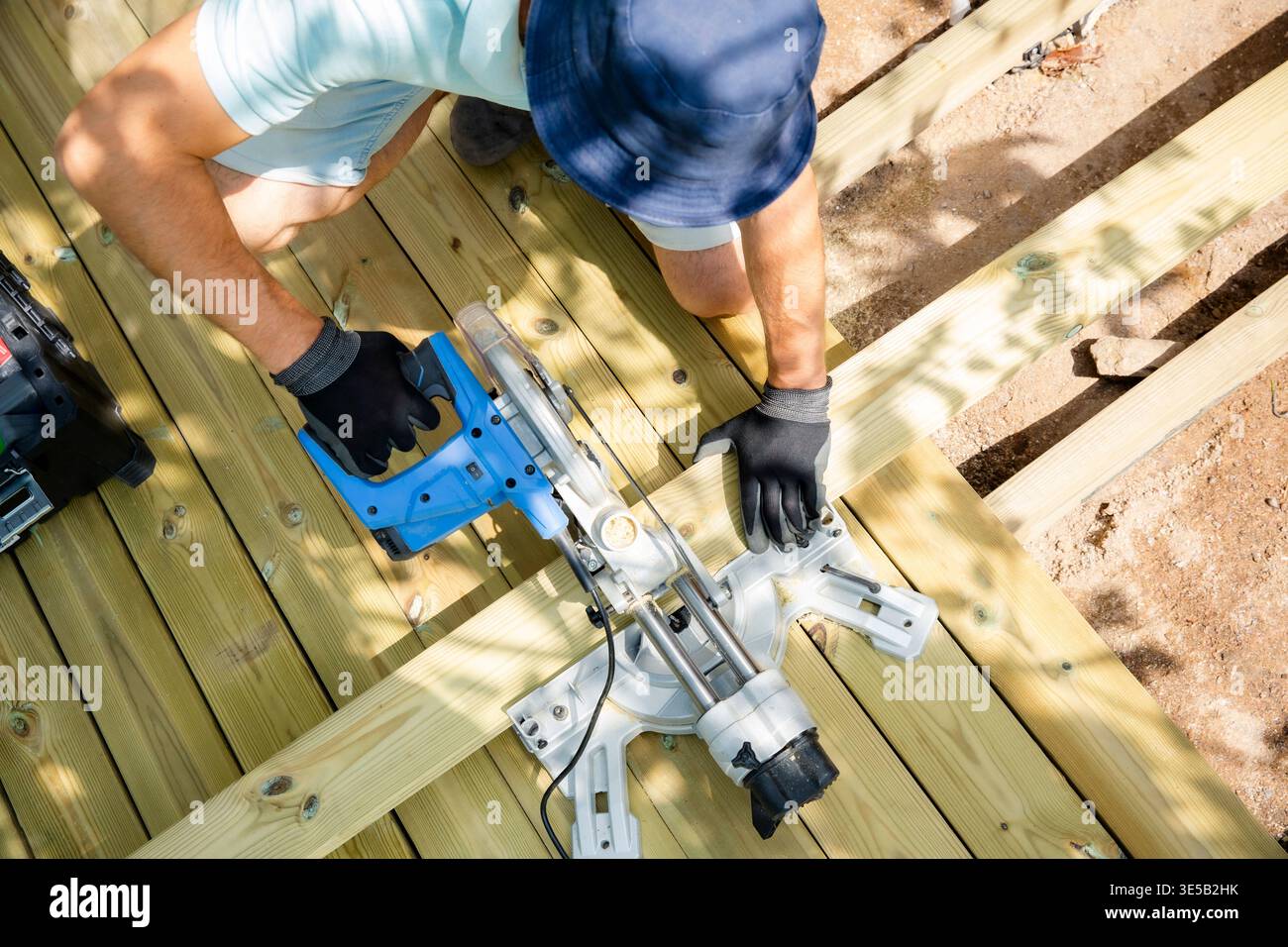 Professional carpenter cutting deck planks with a miter saw during ...