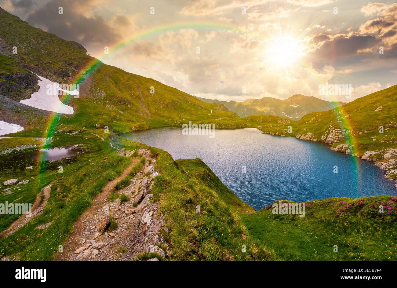 gorgeous summer sunset over capra lake. breathtaking evening view of transylvaia alps in romania. composite background image with rainbow in nature fo Stock Photo