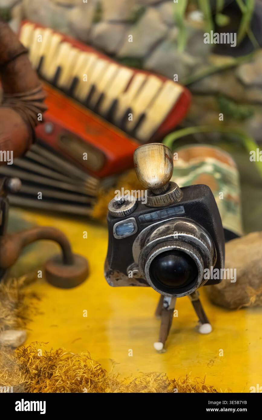 Miniature vintage camera with a flash light standing on a yellow surface next to musical instruments Stock Photo