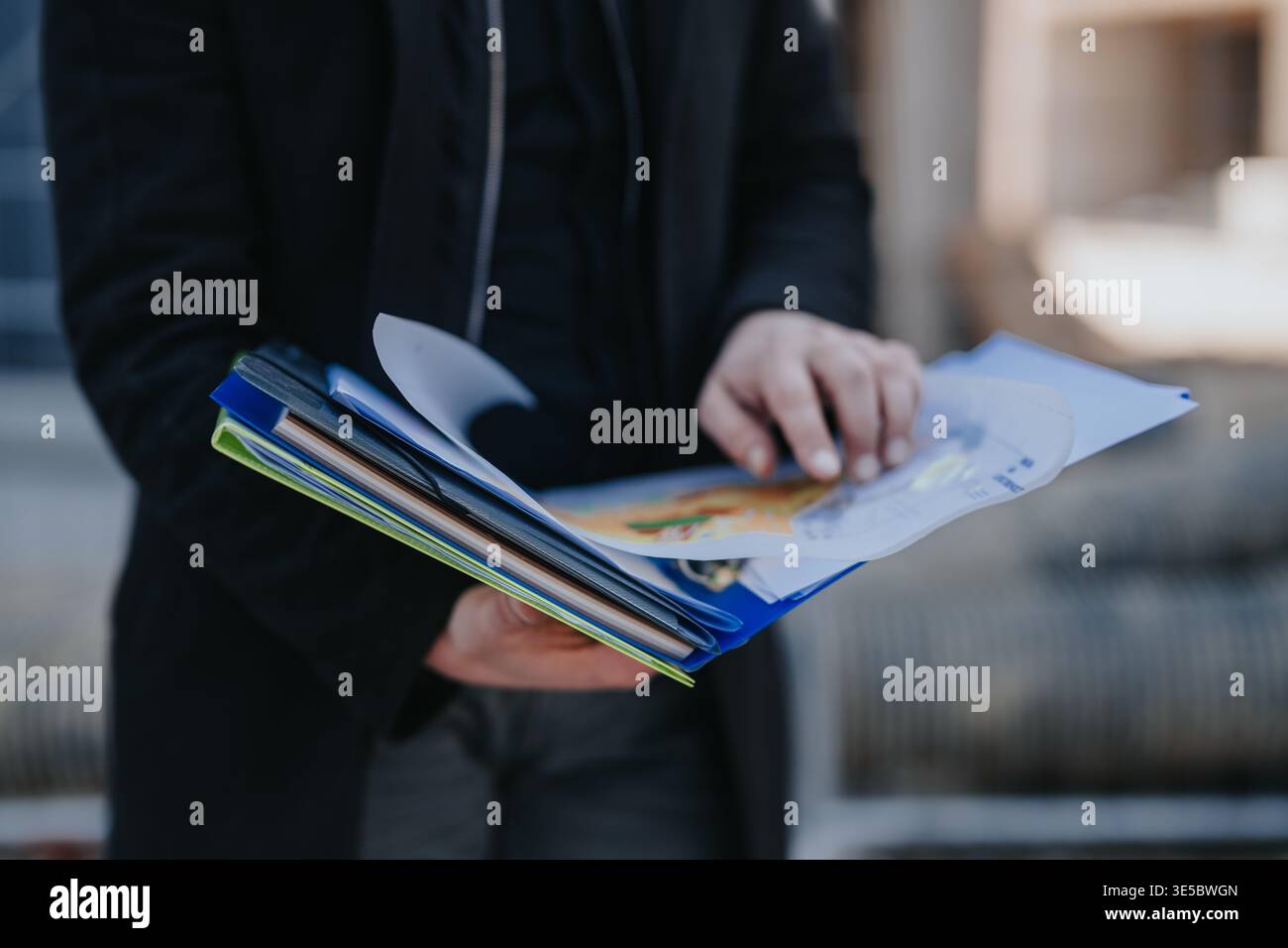 Construction engineer reviewing project plans and documents outdoors while pointing at building drawings Stock Photo