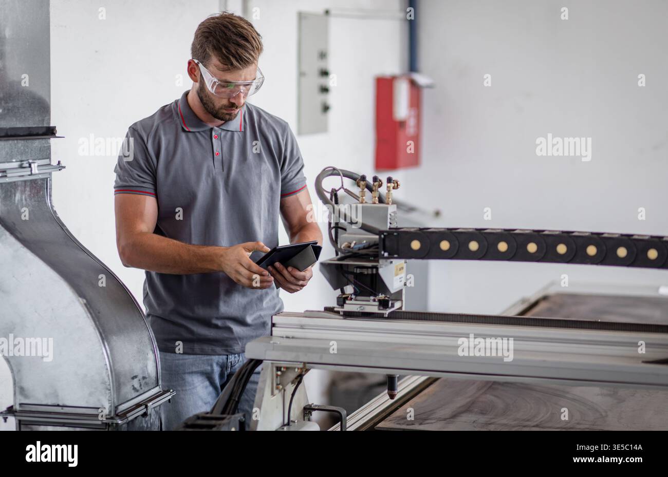Male engineer setup plasma cutter for work in metalwork workshop. Stock Photo