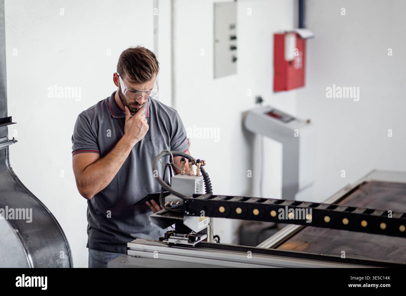 Male engineer setup plasma cutter for work in metalwork workshop. Stock Photo