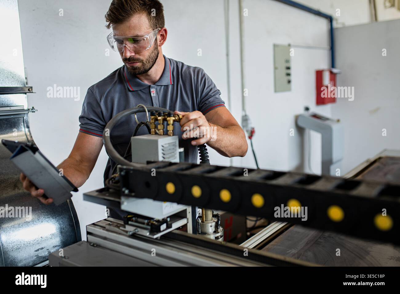 Male engineer setup plasma cutter for work in metalwork workshop. Stock Photo