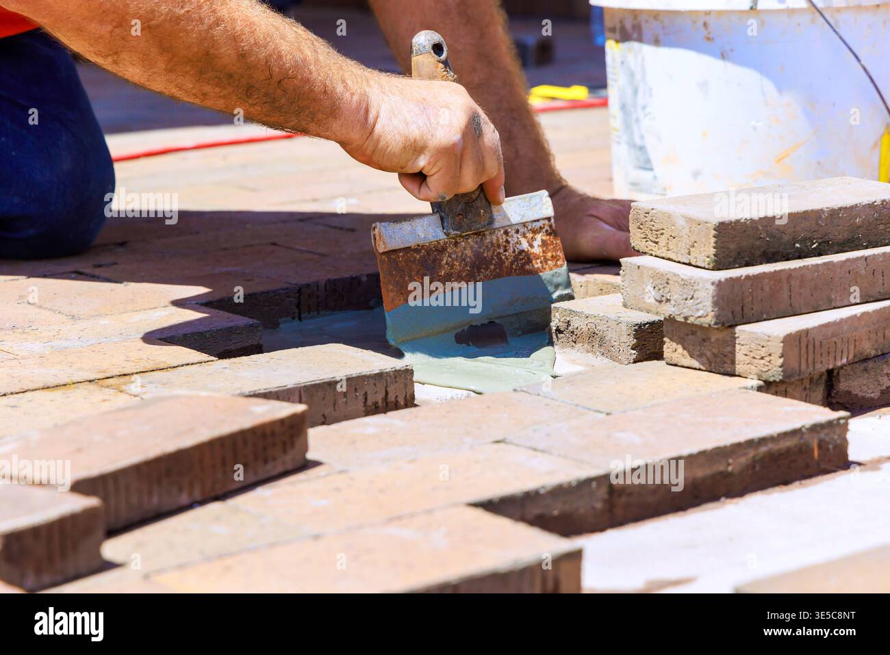 Contractor applies mortar with trowel while arranging bricks on construction site Stock Photo