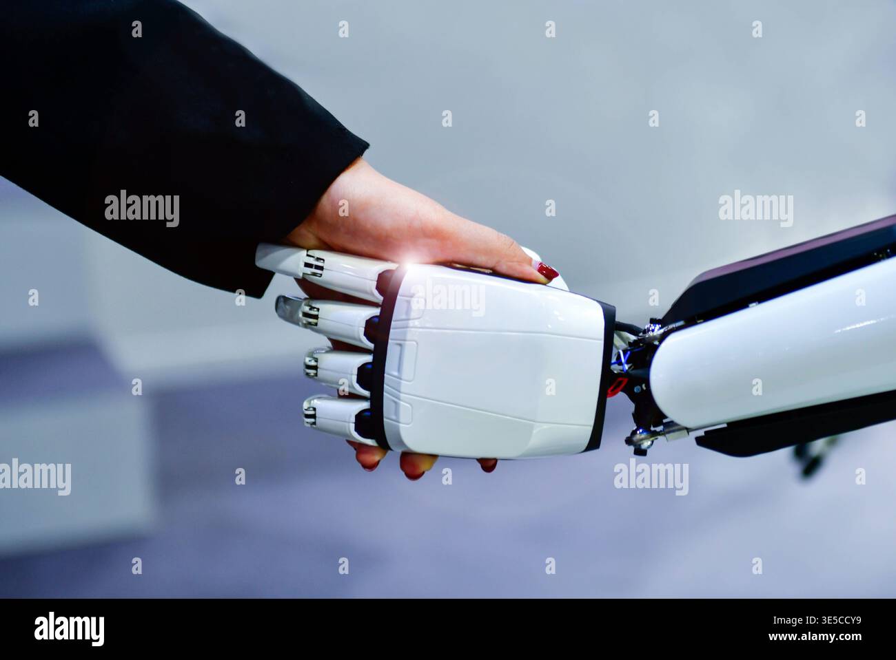 Advanced bionic robotic hand shaking hands with human, symbolizing AI and human collaboration. Stock Photo