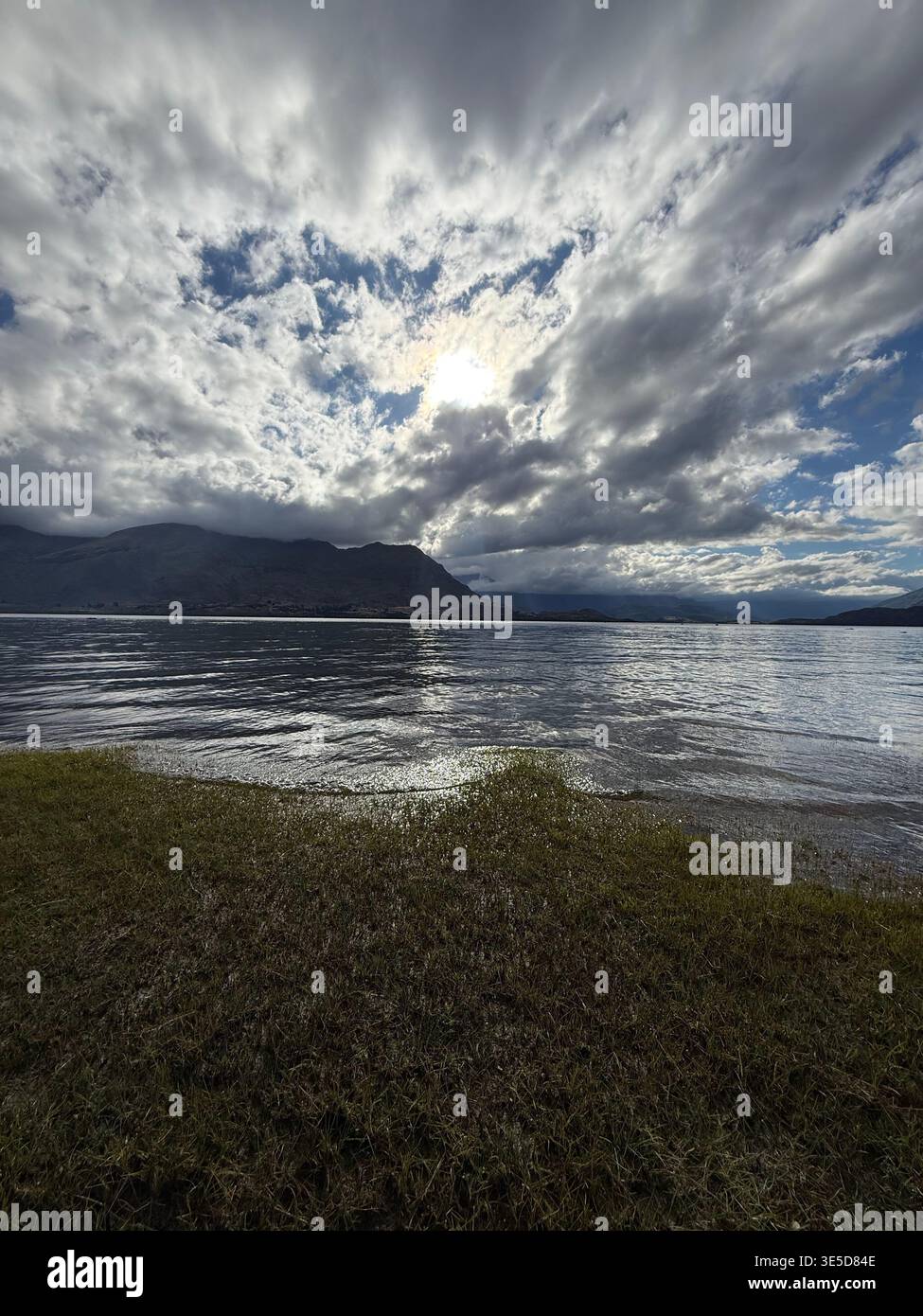 Dramatic cloudy sky over Lake Wanaka with bright sun breaking through, South Island, New Zealand - Smartphone Captured Stock Image