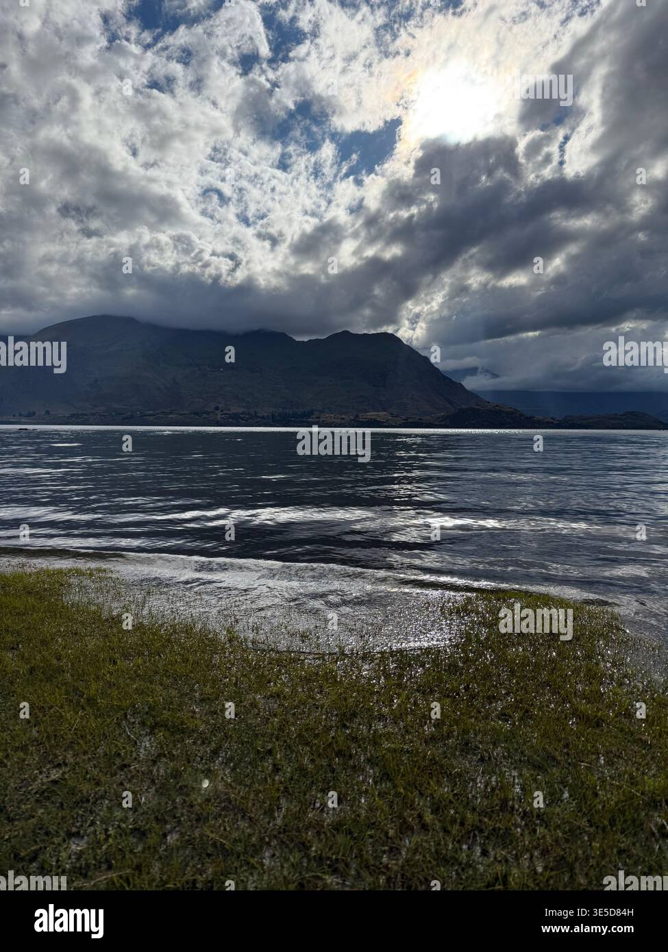 Dramatic cloudy sky over Lake Wanaka with bright sun breaking through, South Island, New Zealand - Smartphone Captured Stock Image