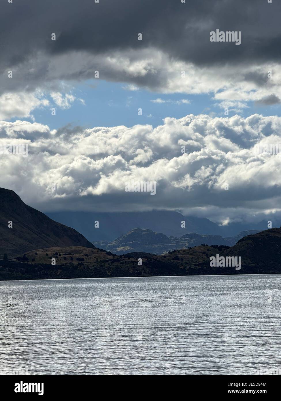 Dramatic cloudy sky over Lake Wanaka with bright sun breaking through, South Island, New Zealand - Smartphone Captured Stock Image