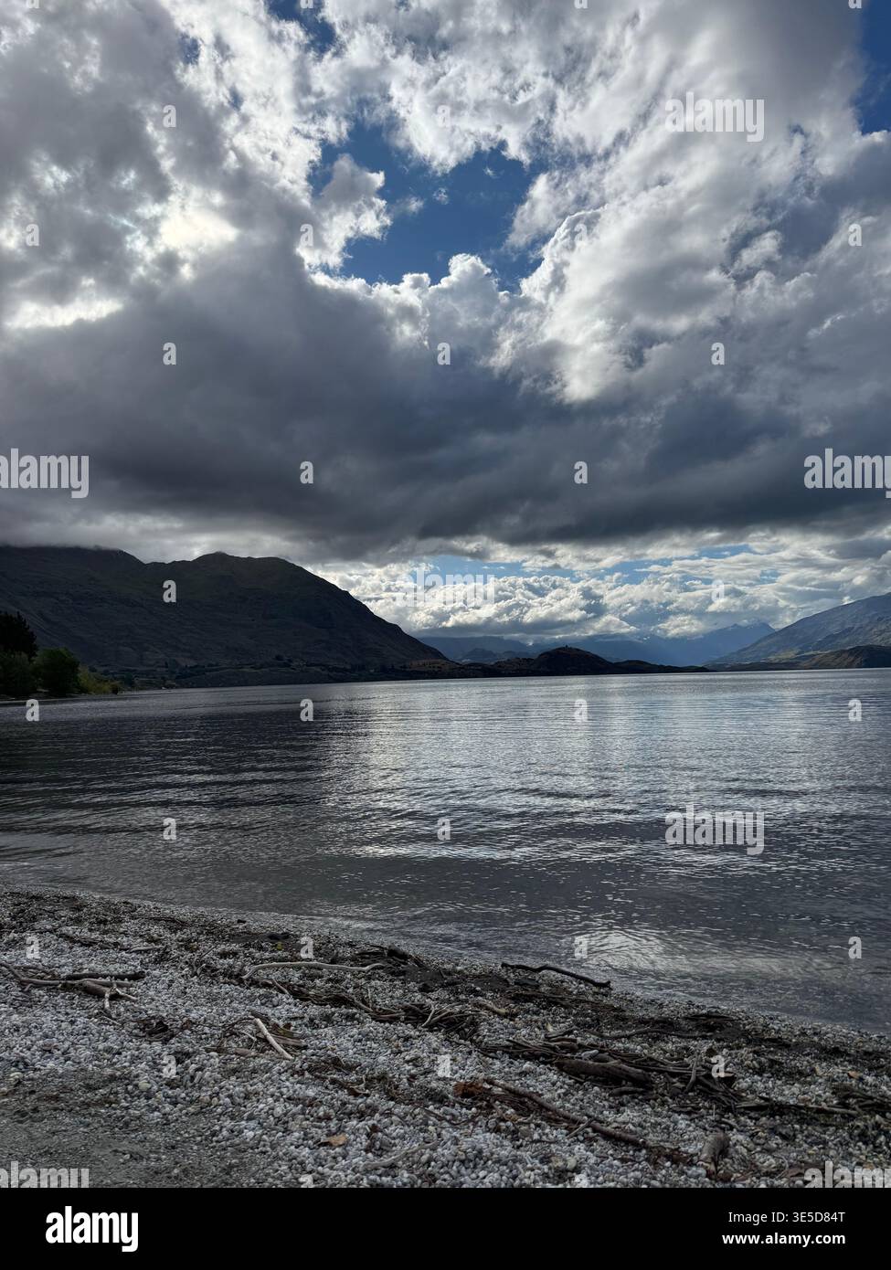 Dramatic cloudy sky over Lake Wanaka with bright sun breaking through, South Island, New Zealand - Smartphone Captured Stock Image