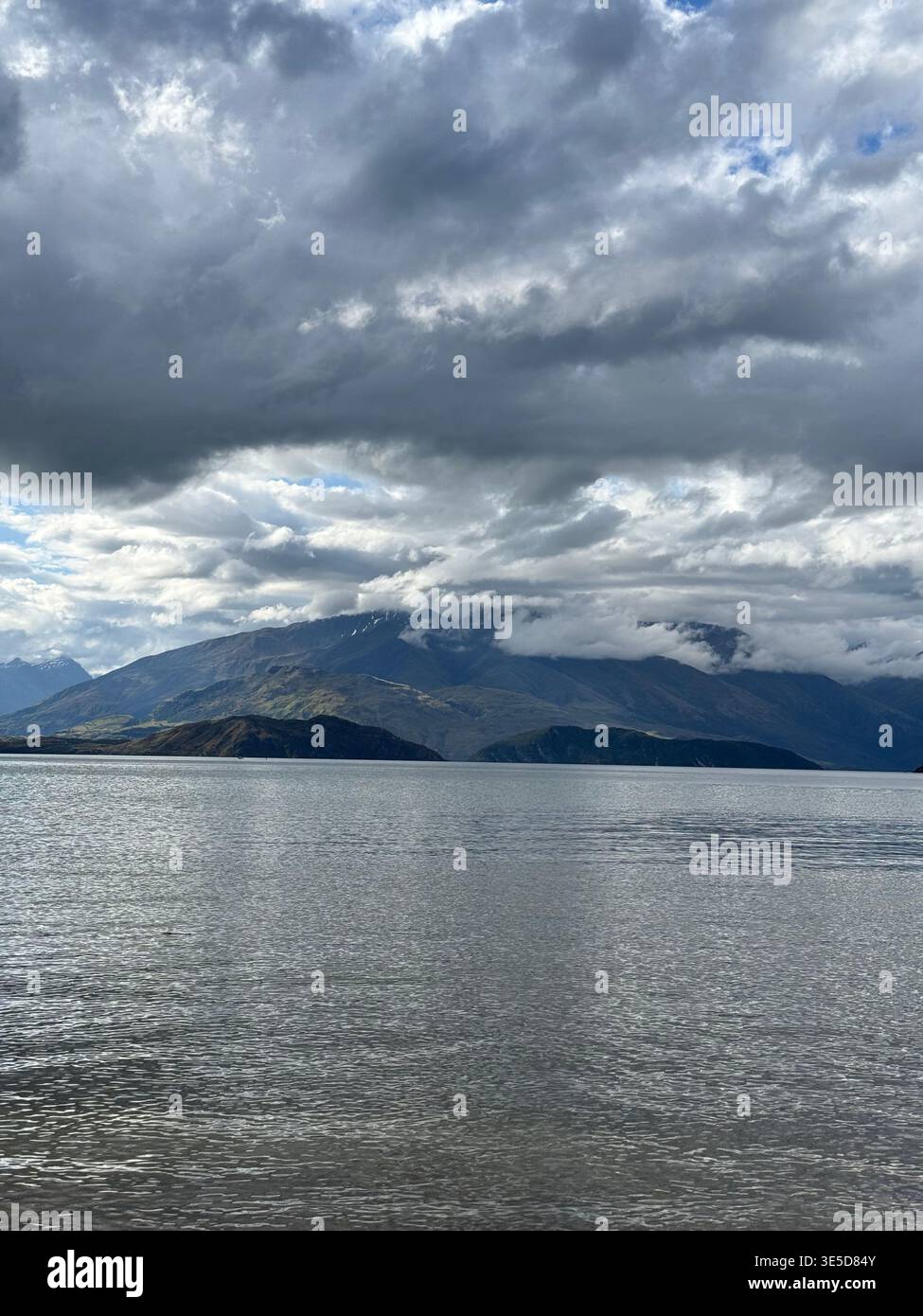 Dramatic cloudy sky over Lake Wanaka with bright sun breaking through, South Island, New Zealand - Smartphone Captured Stock Image