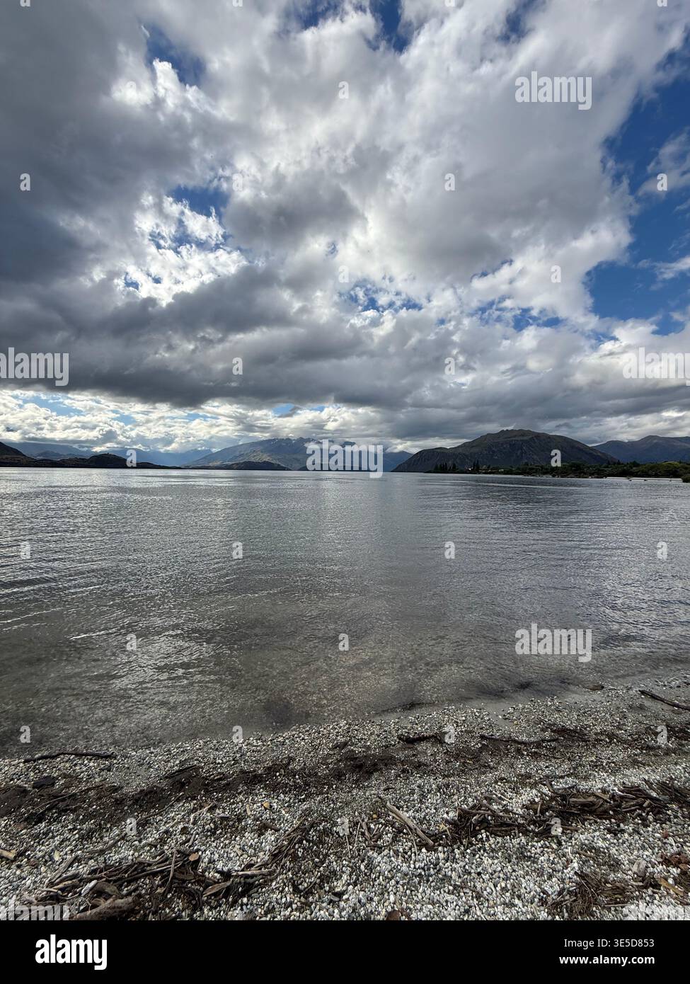 Dramatic cloudy sky over Lake Wanaka with bright sun breaking through, South Island, New Zealand - Smartphone Captured Stock Image