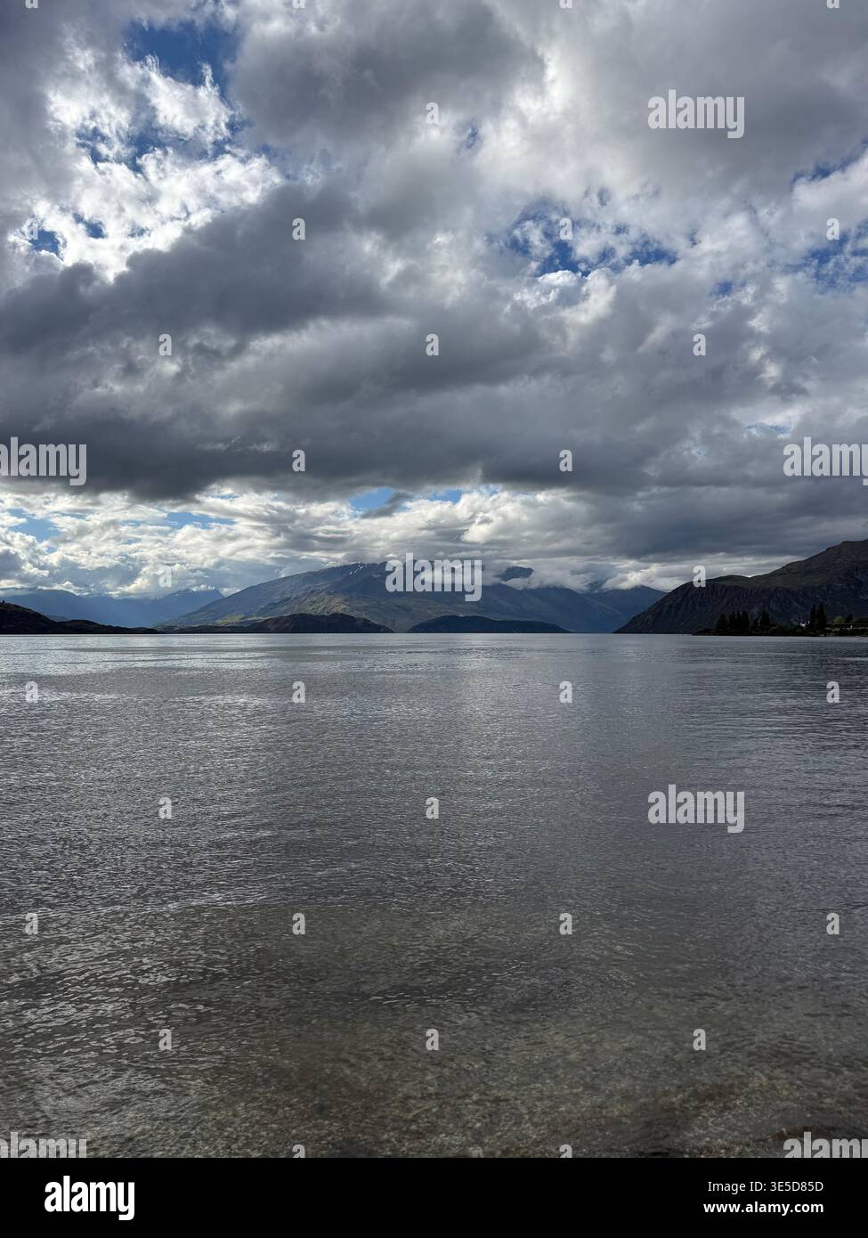 Dramatic cloudy sky over Lake Wanaka with bright sun breaking through, South Island, New Zealand - Smartphone Captured Stock Image