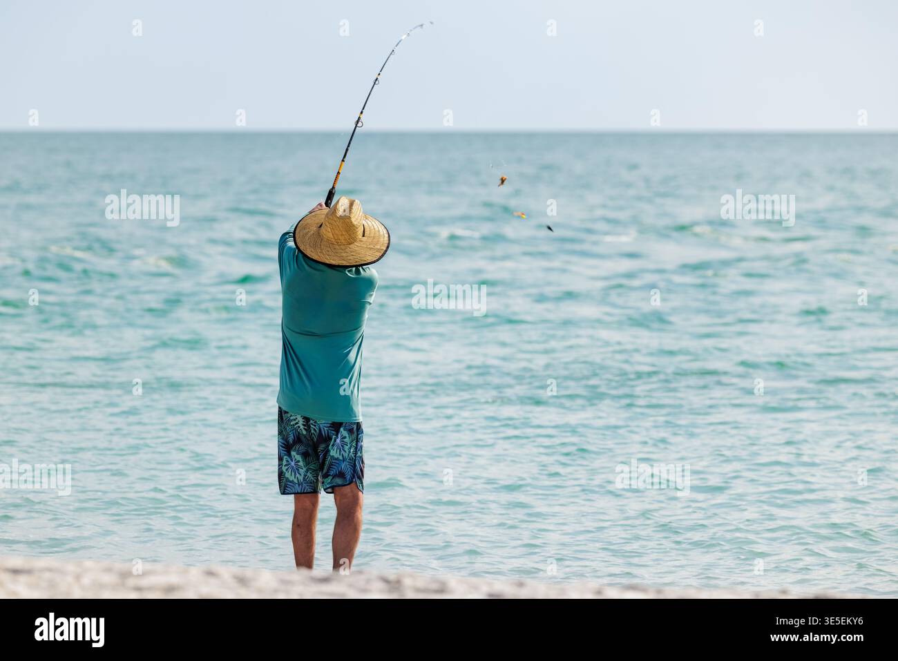 Saltwater fisherman fishing from the beach. Man surf cast fishing from the shoreline of the Gulf of America, Florida. Stock Photo