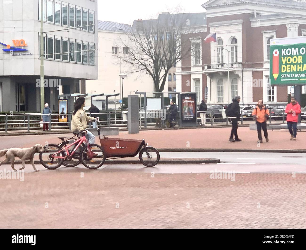 Modern office buildings and public transport at a busy plaza in the Hague Netherlands with pedestrians and cyclists moving through the urban space - Smartphone Captured Stock Image