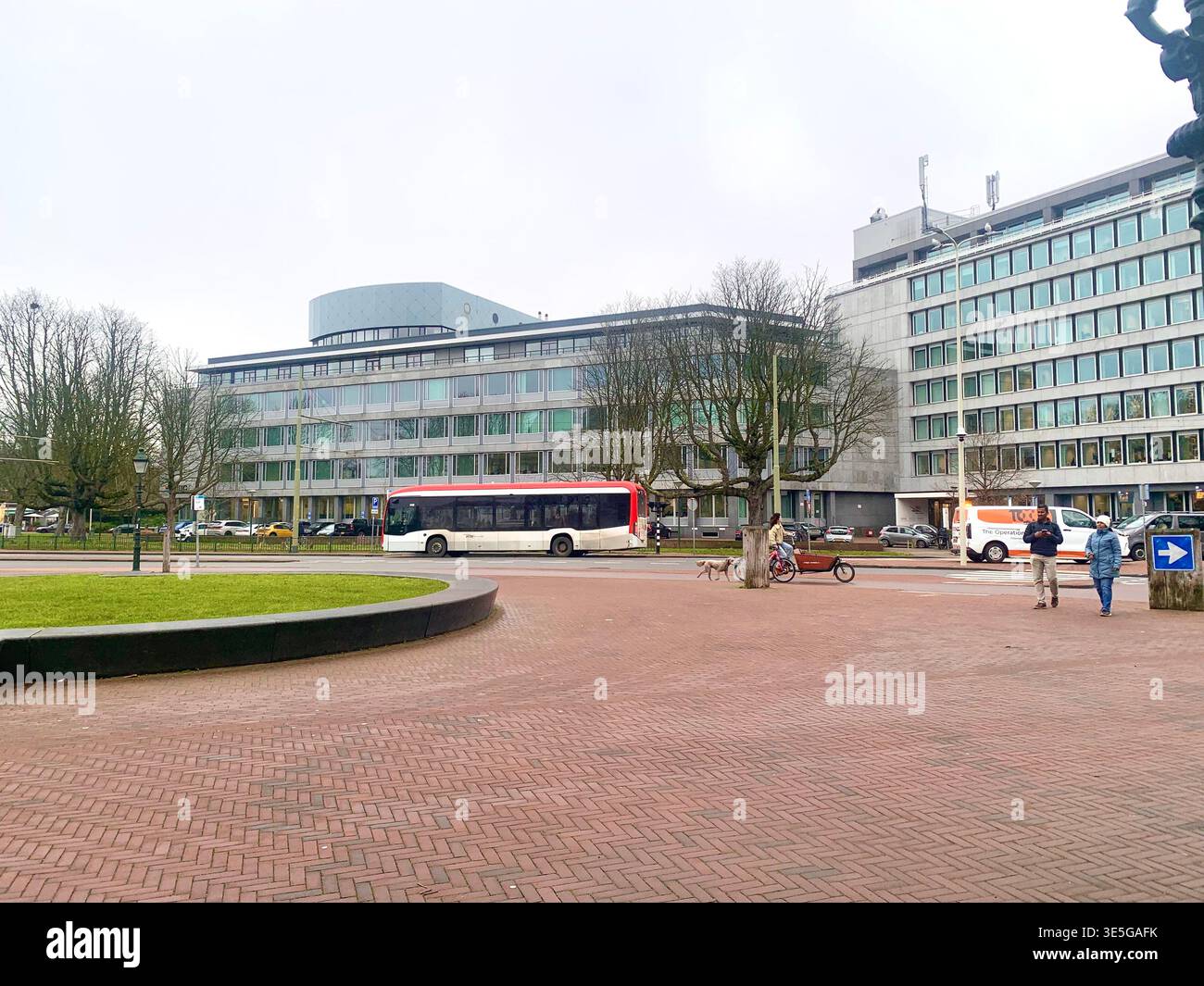 Modern office buildings and public transport at a busy plaza in the Hague Netherlands with pedestrians and cyclists moving through the urban space - Smartphone Captured Stock Image