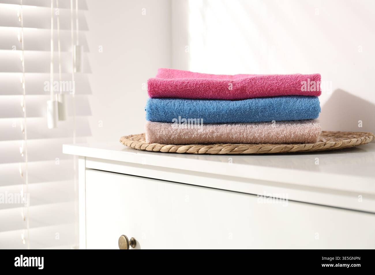 Stack of colorful towels on white dresser indoors Stock Photo