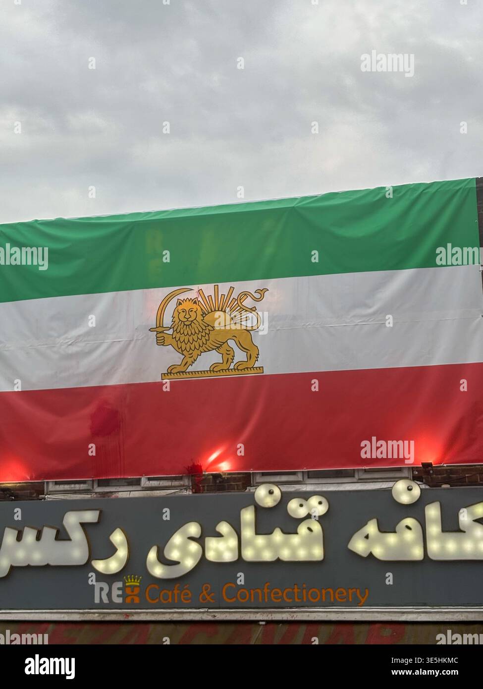 Iranian flag with Lion and Sun emblem outside a persian cafe and confectionery in North Finshley London know as Little Tehran - Smartphone Captured Stock Image
