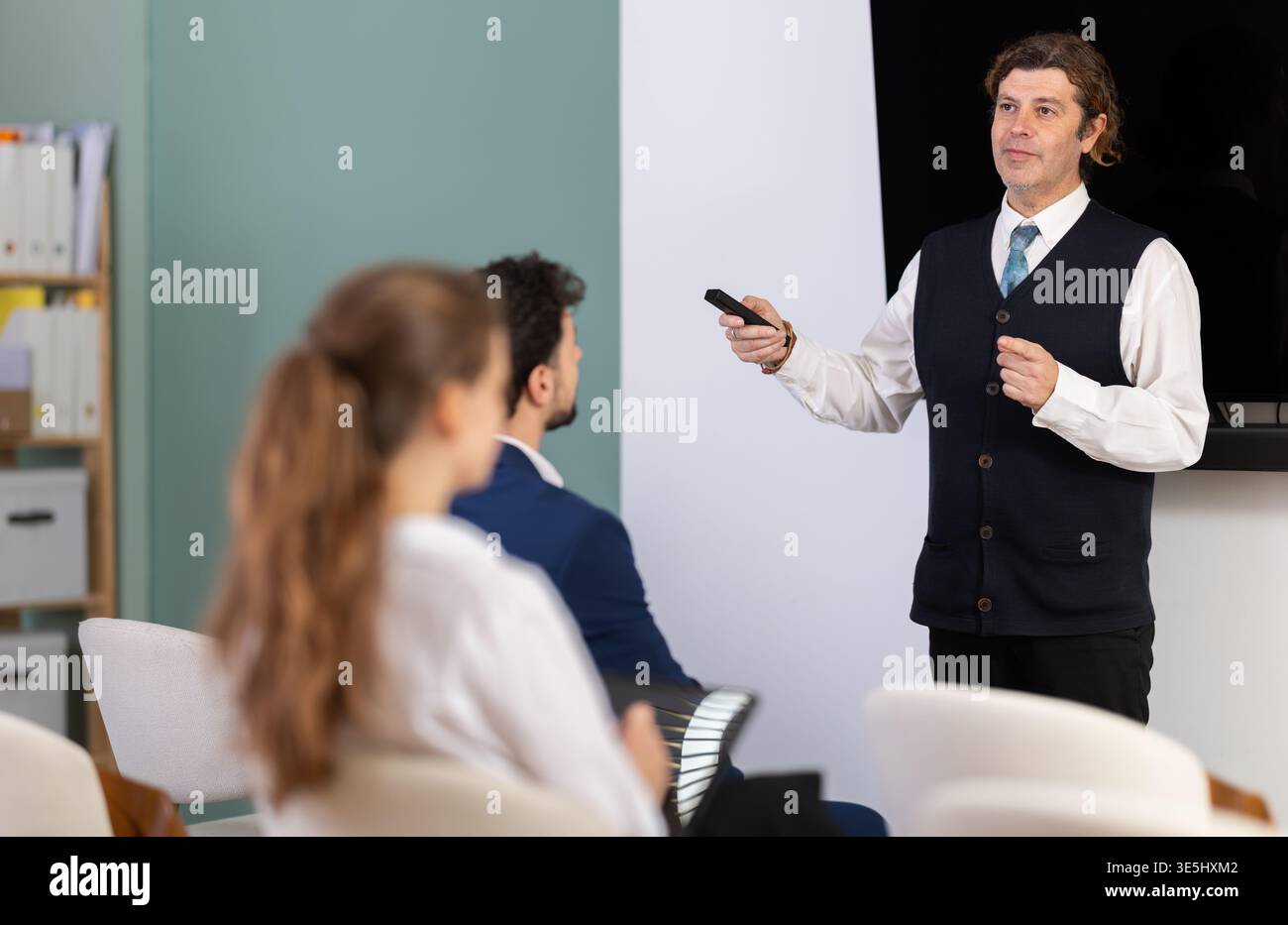 Male business trainer explaining topic to professionals using digital board Stock Photo