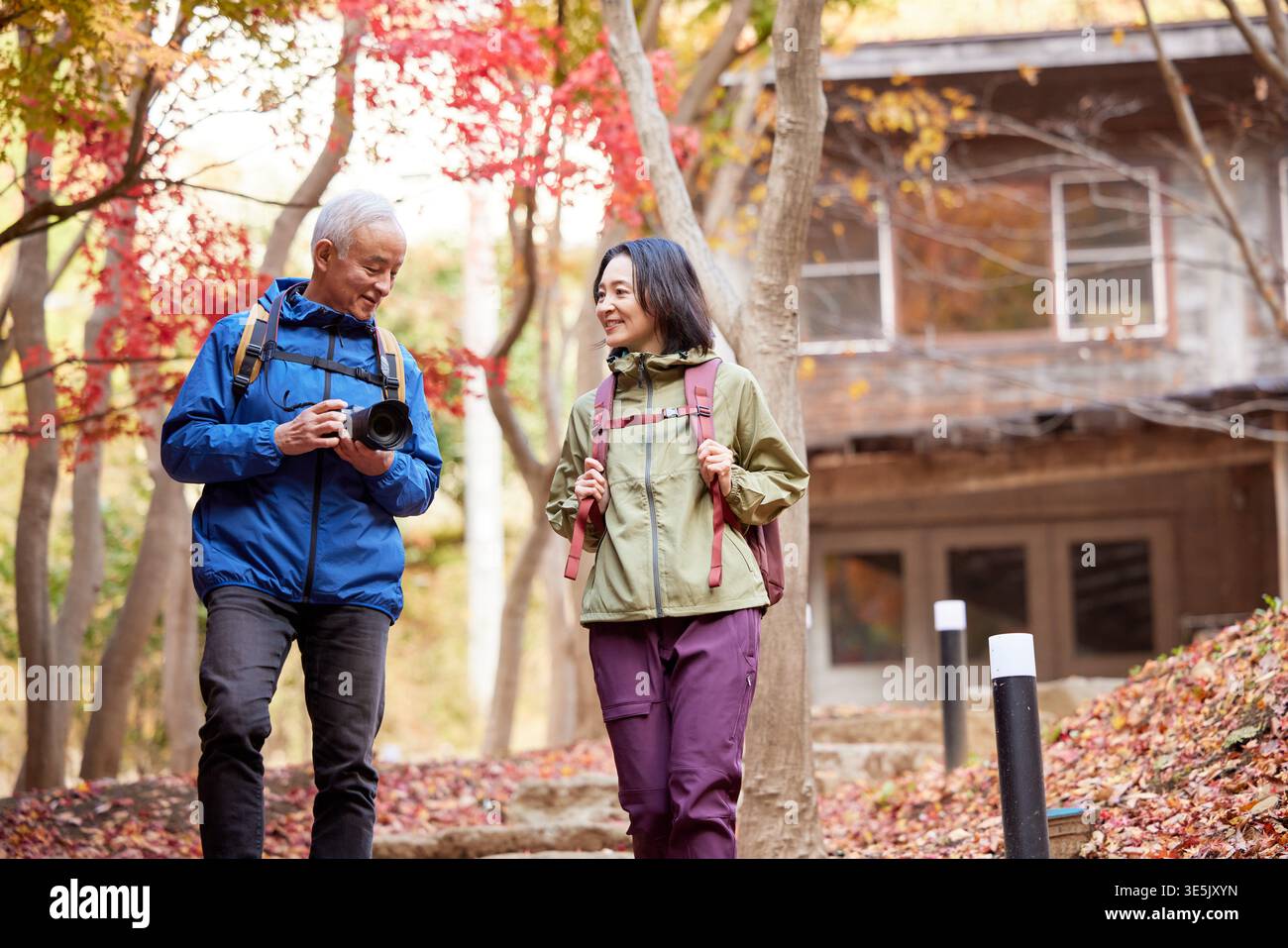 Smiling Japanese senior couple on autumn hike with camera Stock Photo