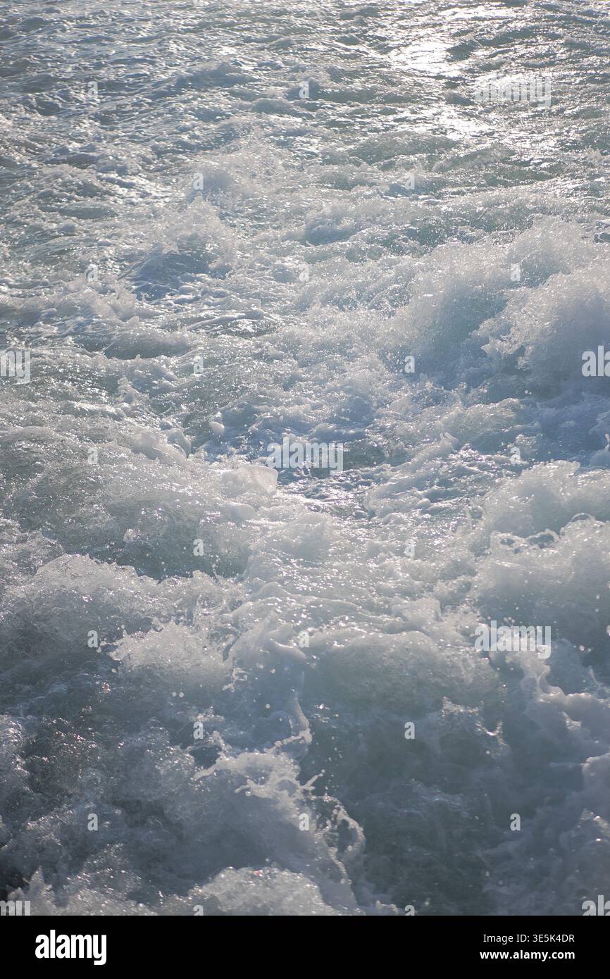 Waves crash on water surface during sunny day Stock Photo