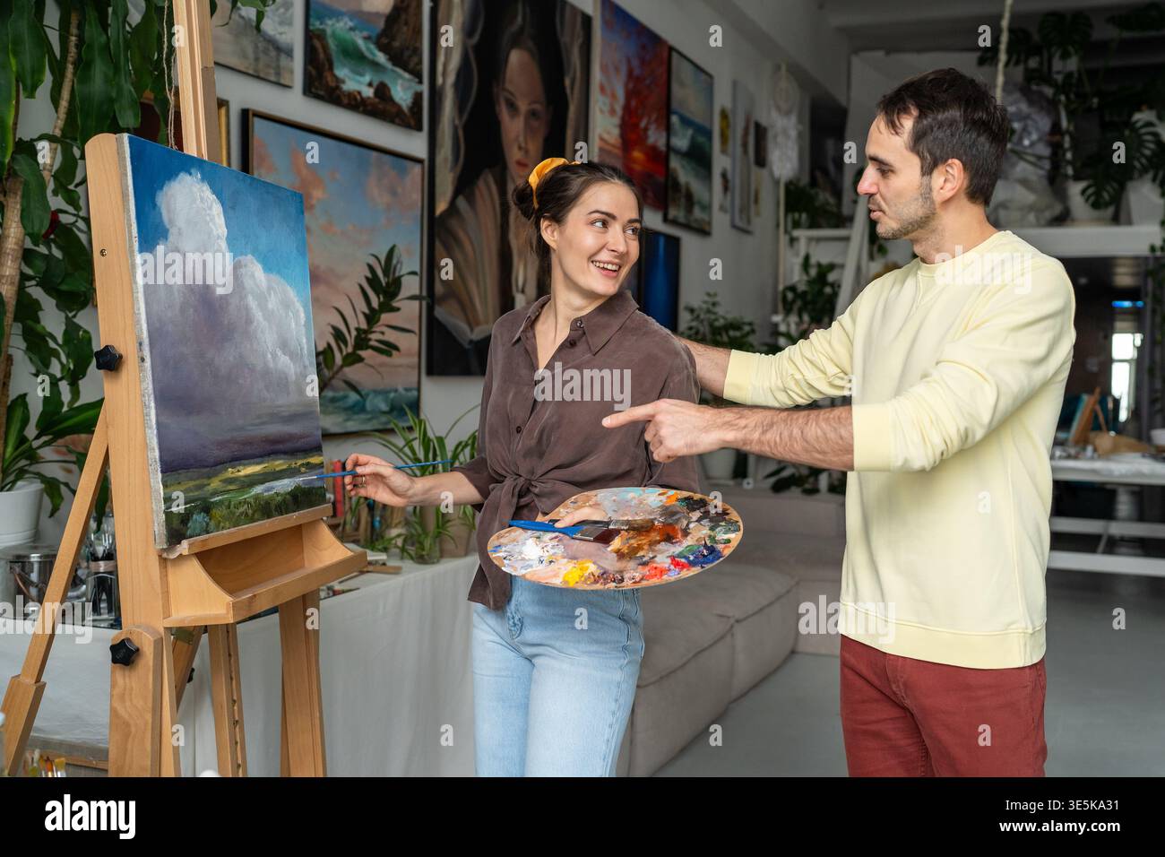 Caring husband showing interest in wife's painting hobby, praises woman painter talent and skills. Stock Photo