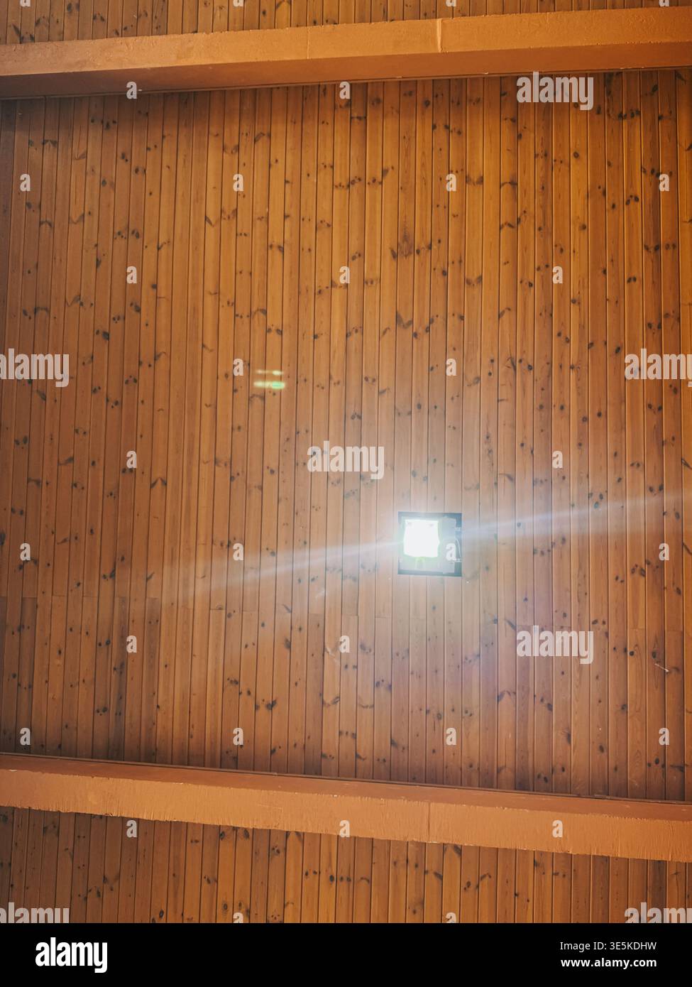 Riga, Latvia - March 31, 2026:Warm wooden ceiling with a central light fixture and visible beams, captured from below. Clean geometric lines and natur Stock Photo