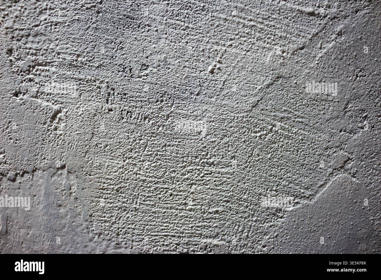 Rough white painted wall texture with strong shadows creating depth and rugged surface patterns Stock Photo