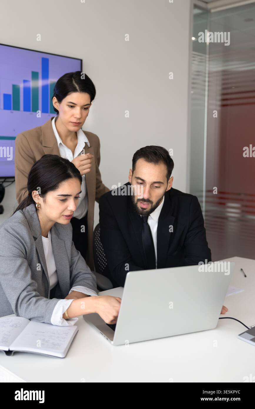 Team analyzing data, discussing corporate strategy on laptop in office Stock Photo