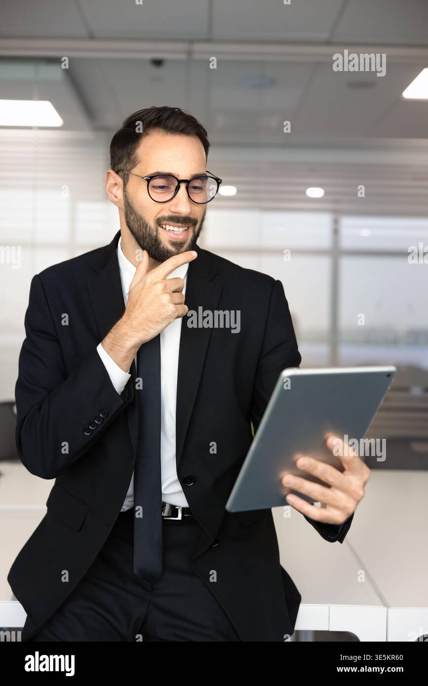 Smiling Hispanic businessman reviewing data on digital tablet Stock Photo