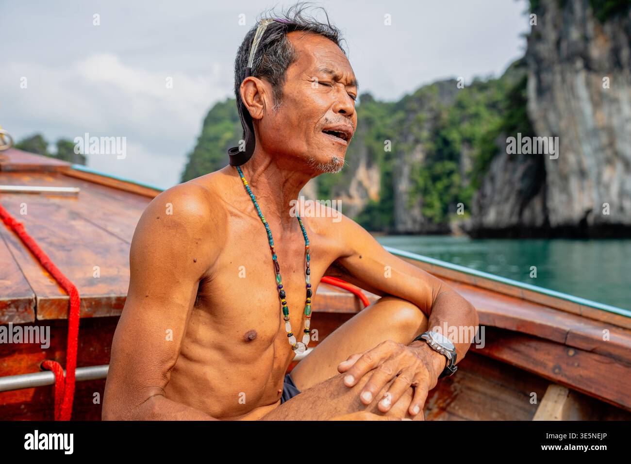 Thai senior man relaxing on traditional longtail boat Stock Photo