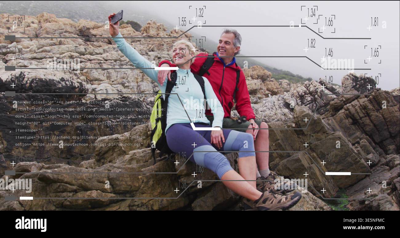 Smiling couple wearing hiking gear sitting on rocky cliff taking selfie with phone, packs, overlays Stock Photo