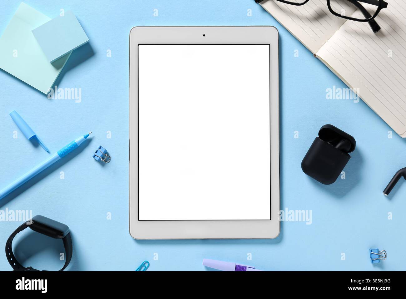 Tablet computer with different modern gadgets and stationery on blue background Stock Photo