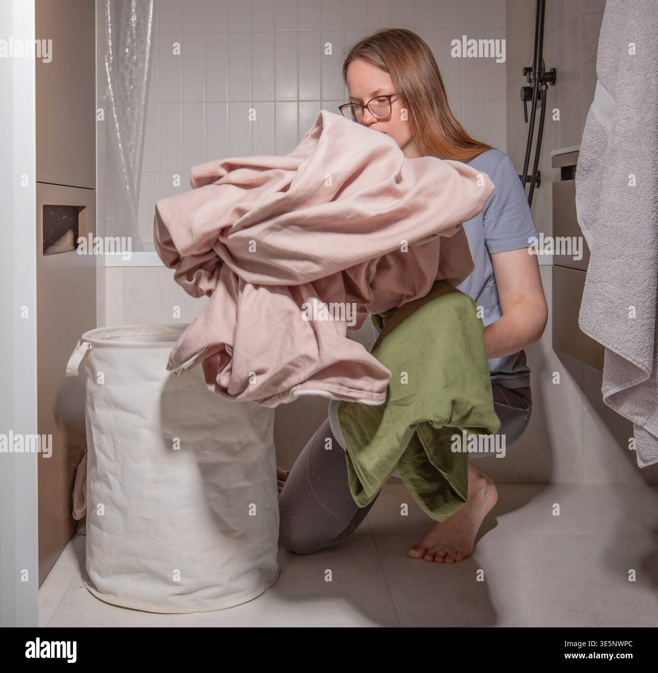 Young woman sorts clean clothes during everyday laundry routine at home ...
