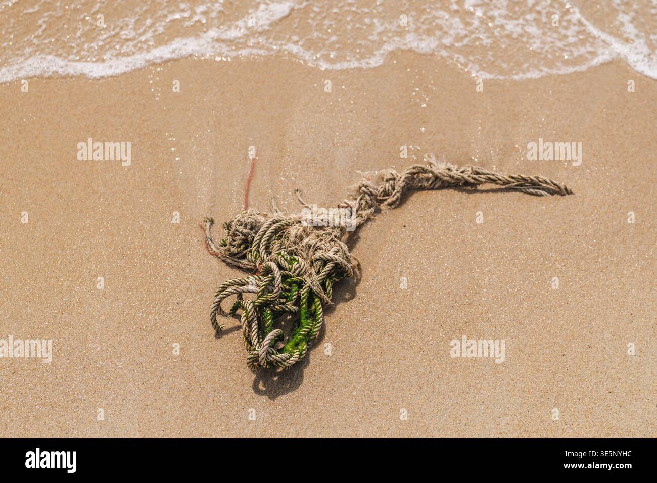 Washed Up Rope Old tangled rope washed ashore on sandy beach with sea waves in Koh ...
