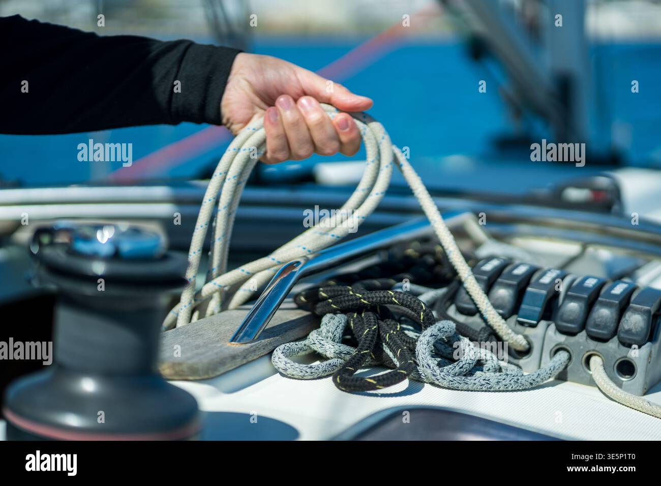 Hand working with rope and winch on sailboat deck Stock Photo
