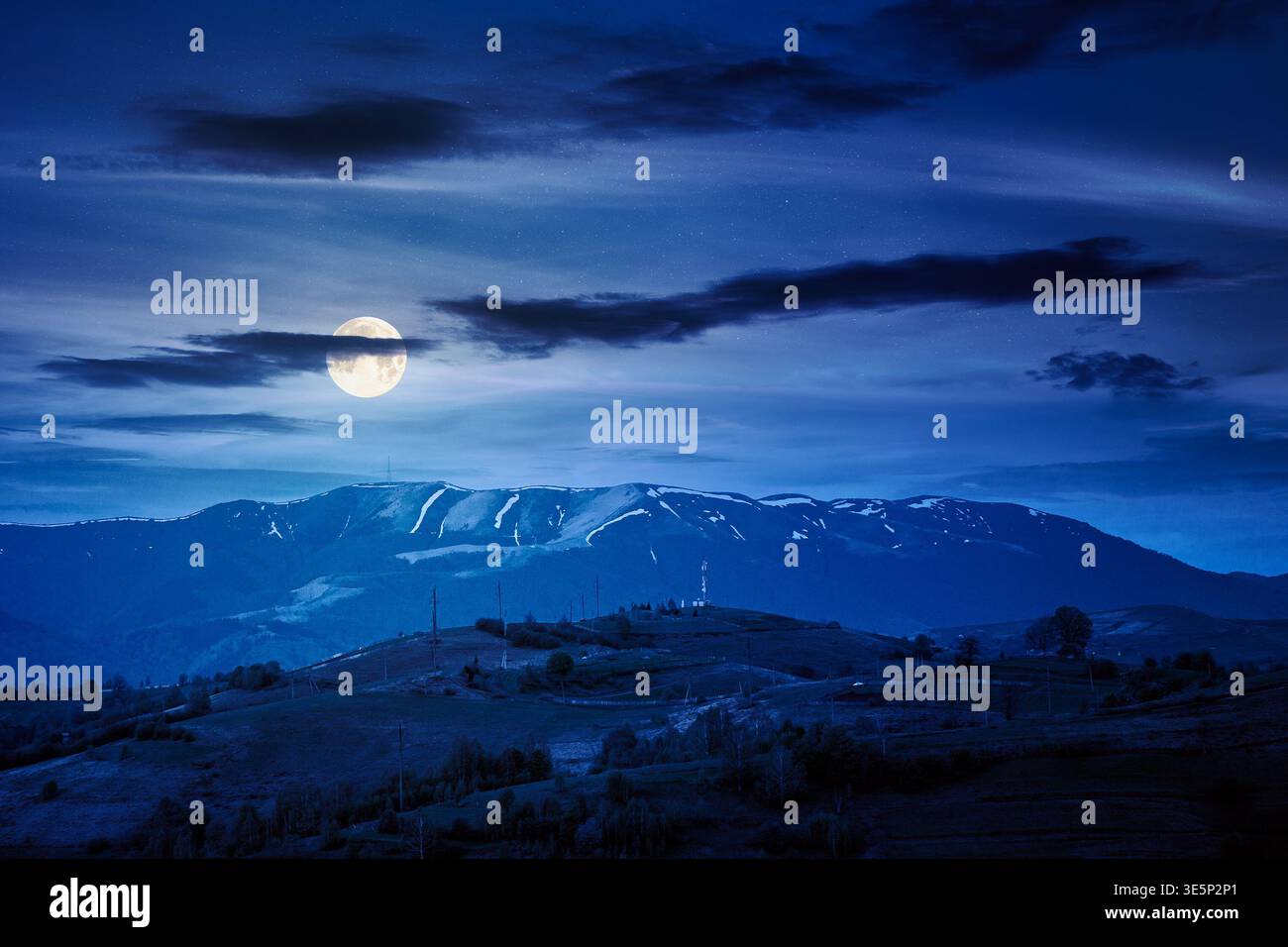mountainous countryside scenery at night. mysterious sky above the distant valley and ridge. full moon over remote meadows and trees on rolling hills. Stock Photo
