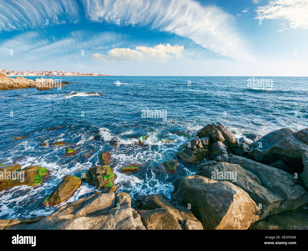 sea coast with stones and boulders in the forenoon. view of beach with rock in seaweed. dynamic cloudscape on the sky over horizon. summer vacations b Stock Photo