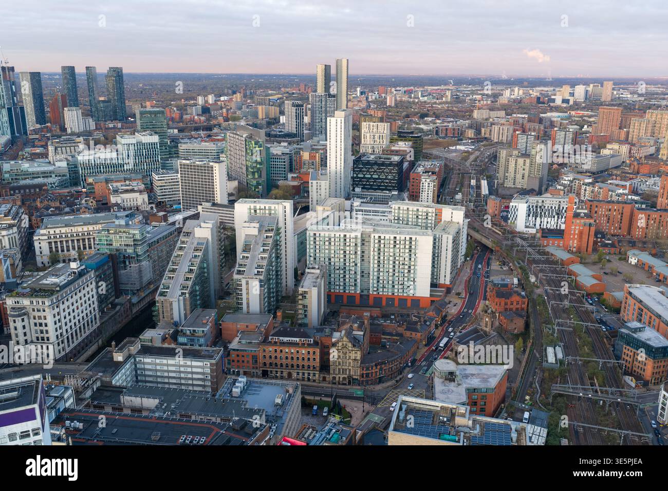 High-angle aerial view showing the railway infrastructure leading to Victoria Station, surrounded by modern skyscrapers at early sunrise. Stock Photo