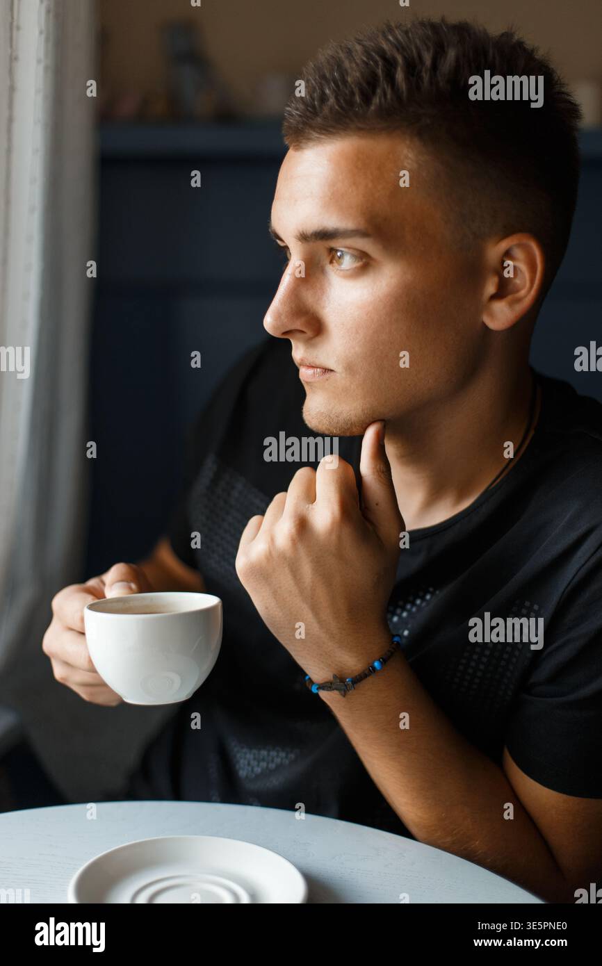 Handsome young man sitting and drinking aromatic coffee Stock Photo