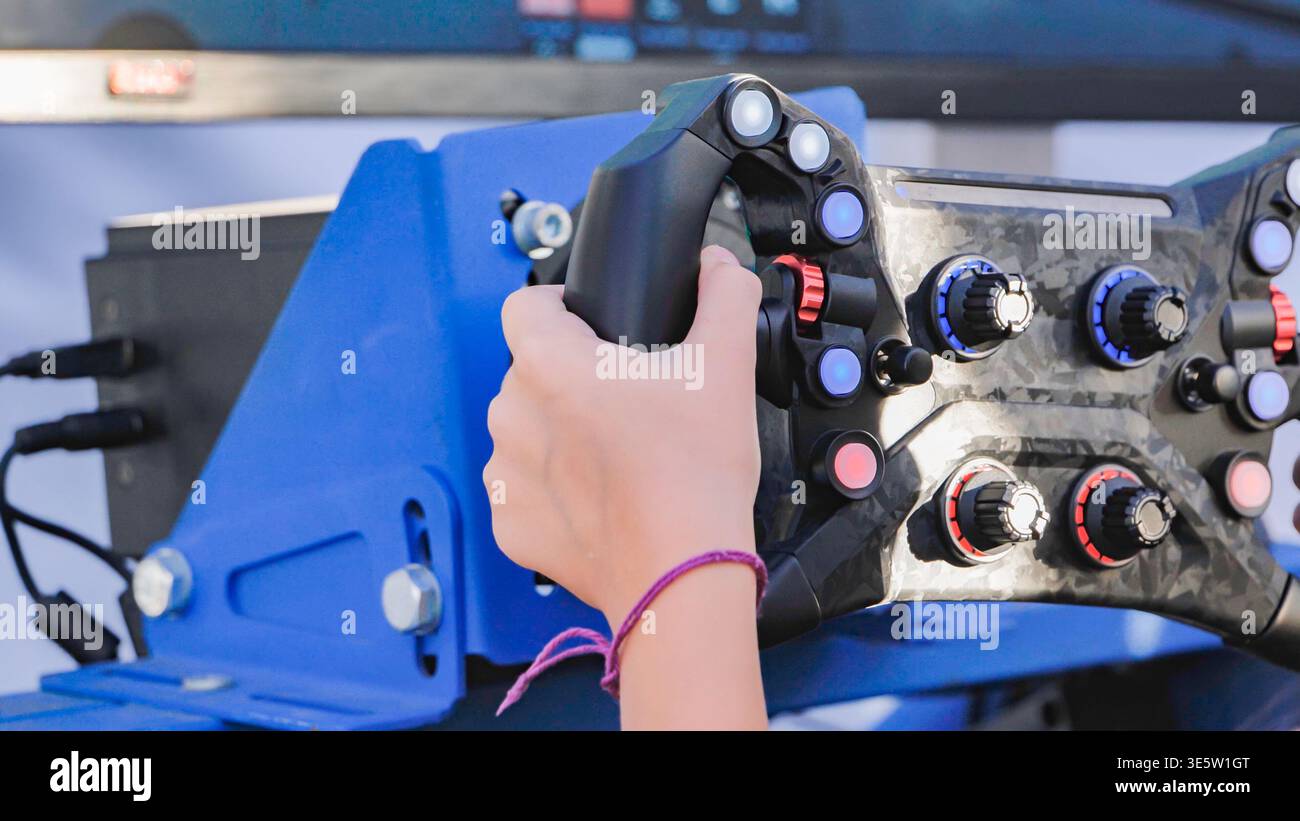 Moscow, Russia - August 25, 2025: Hand on a Simagic racing wheel, experiencing virtual car racing simulation Stock Photo
