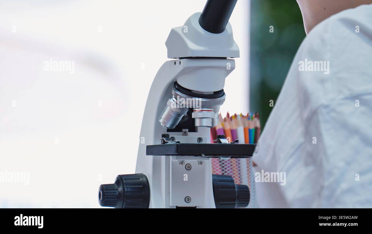 Student learning science using microscope in a school laboratory for education and research Stock Photo
