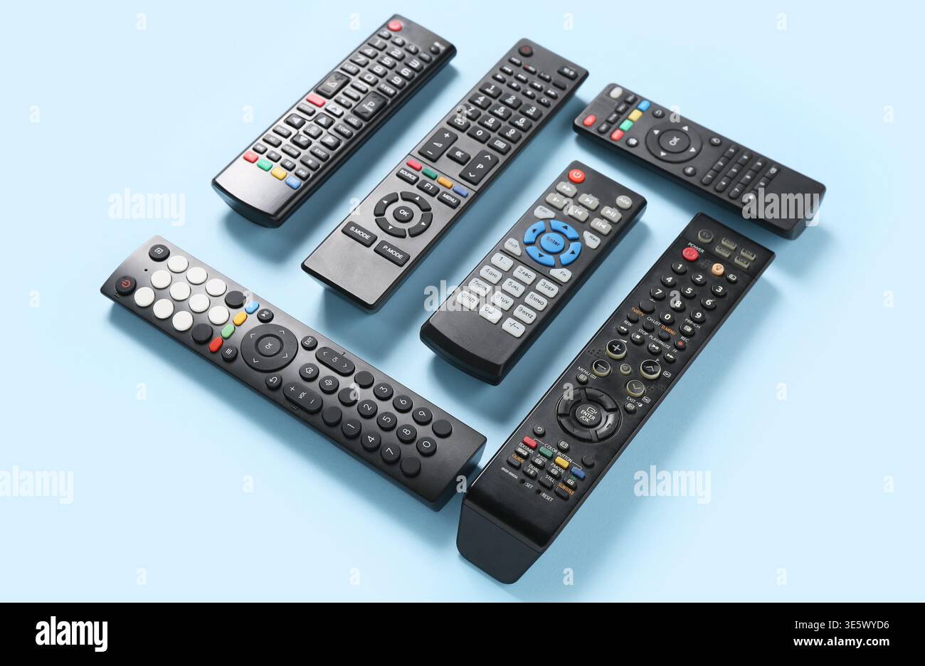 Different modern TV remote controls on blue background Stock Photo