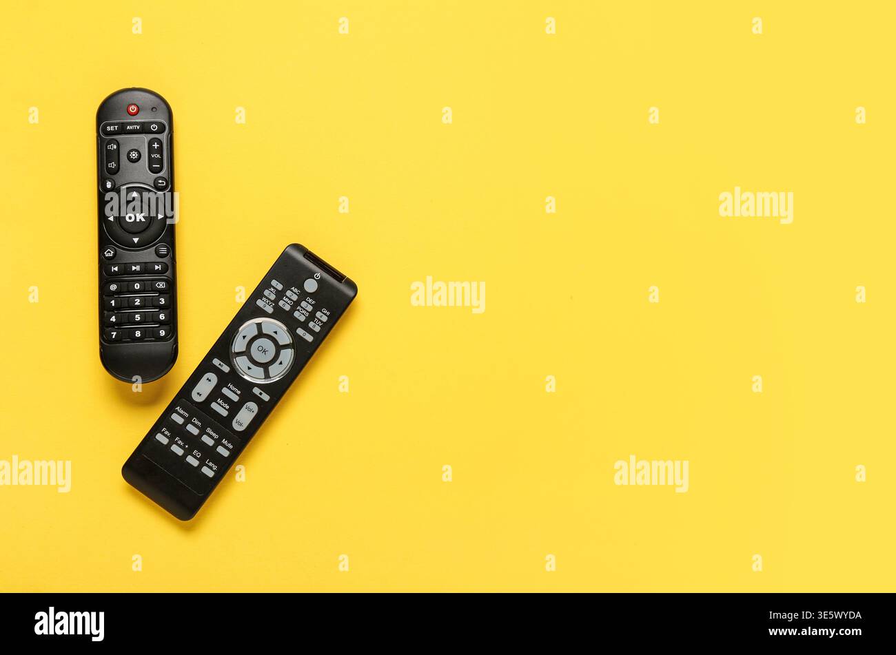Different modern TV remote controls on yellow background Stock Photo