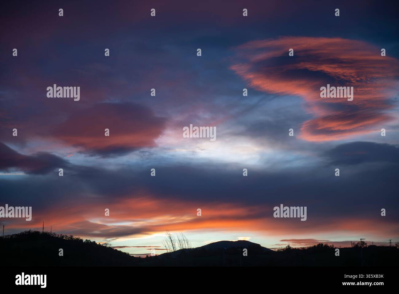 Colorful sunset sky with dramatic clouds over mountain horizon Stock Photo