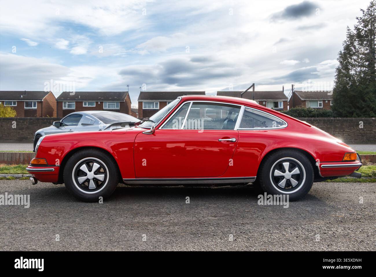 A vintage red Porsche 911 coupe parked on gravel with its distinctive round headlights and Fuchs style wheels during an outdoor car event Stock Photo